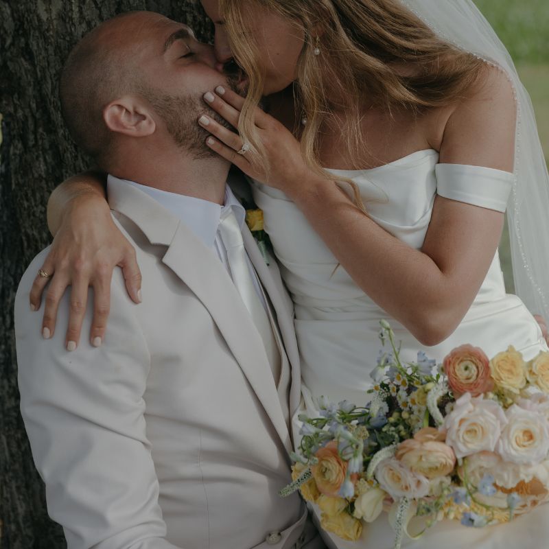 Bride kissing her groom with her bridal bouquet on her lap